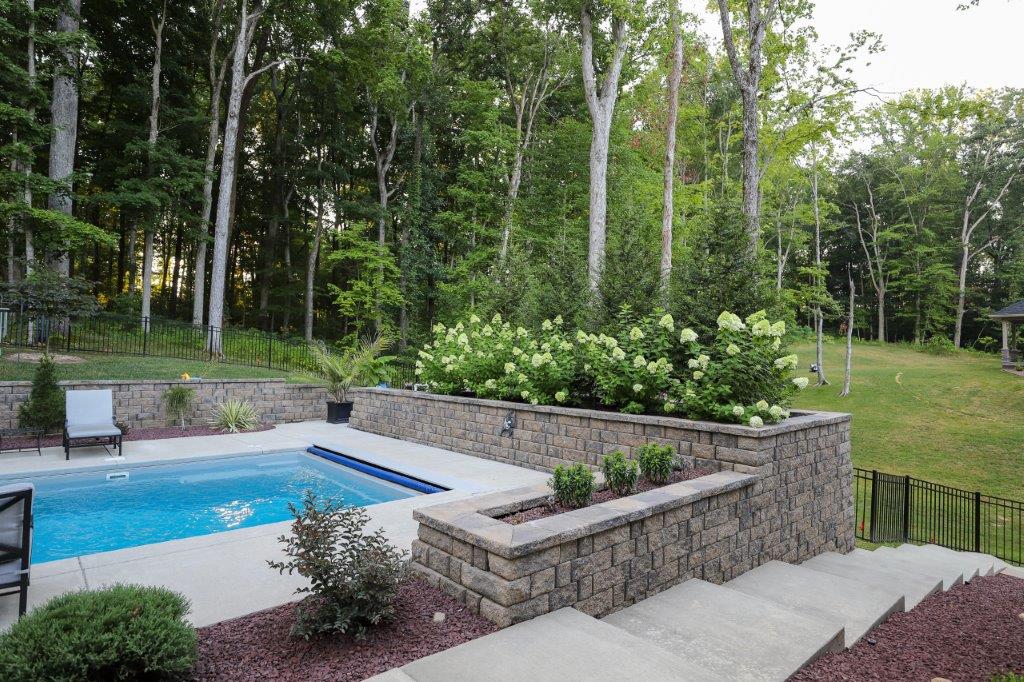 Retaining wall and paved stairway next to fiberglass pool