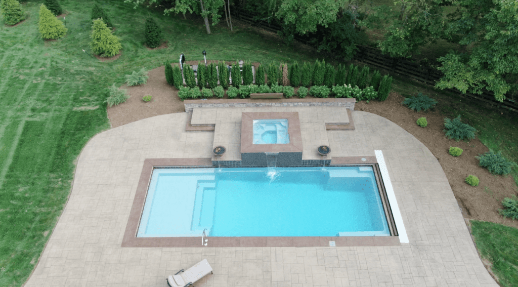 Inground fiberglass swimming pool with fountain spa and stone patio