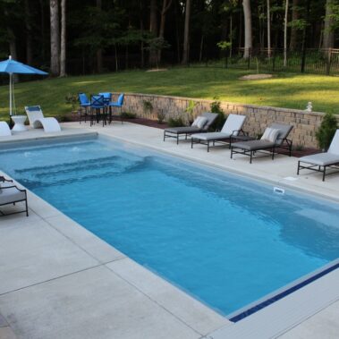Fiberglass pool with cover, patio and lounge chairs