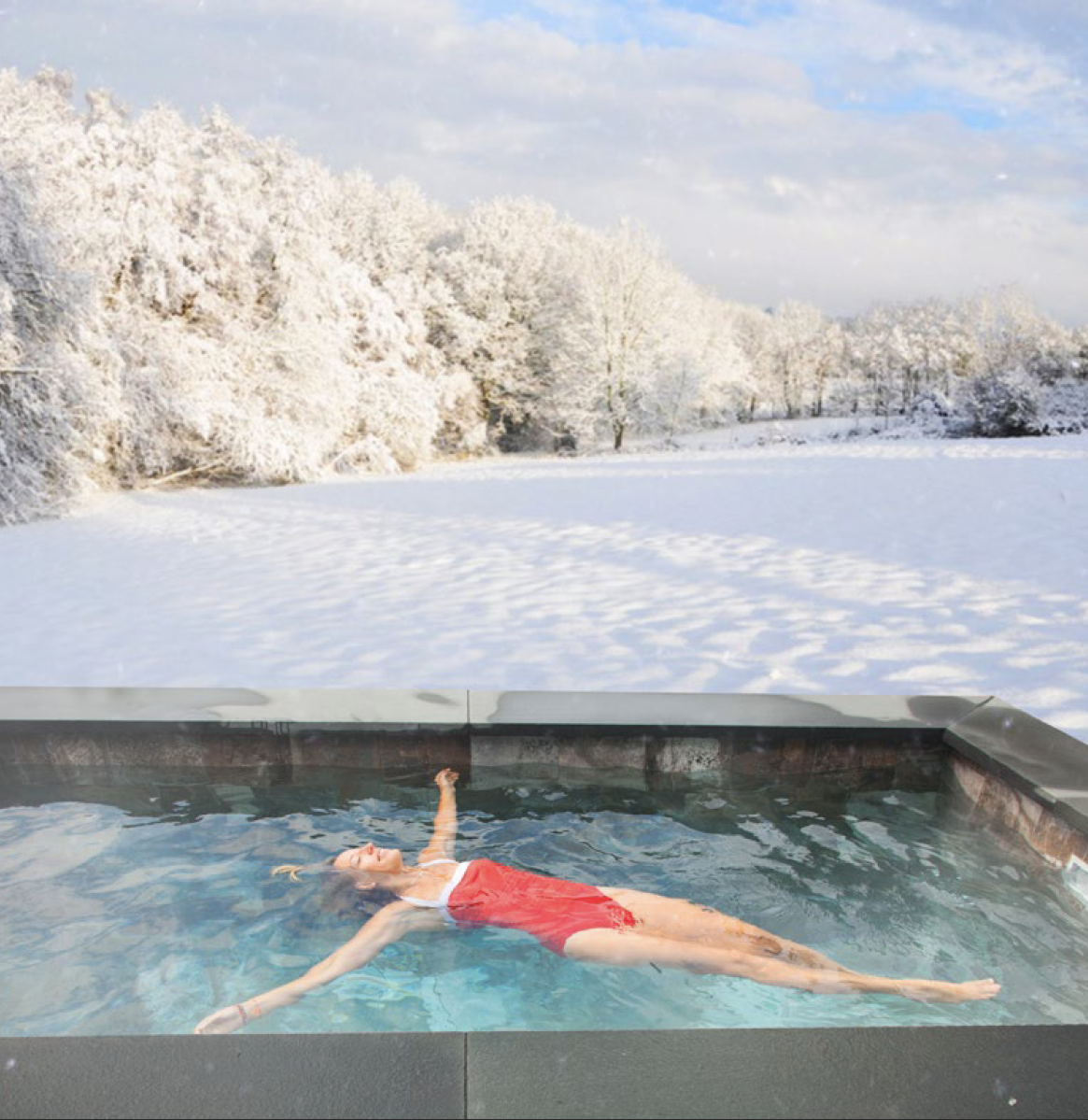 Woman floating in cocktail pool in the winter with snow on the ground