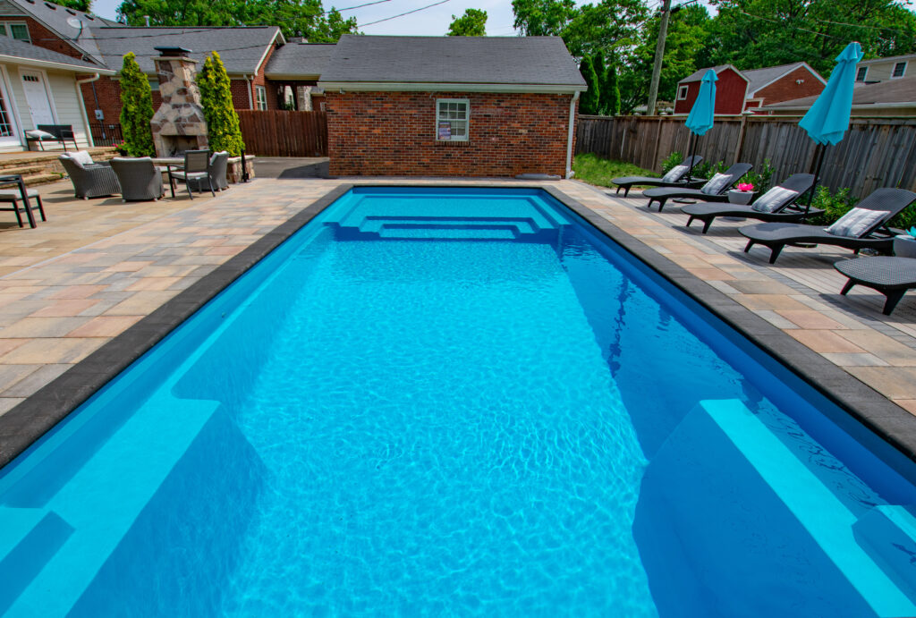 Long rectangular fiberglass pool in front of pool house