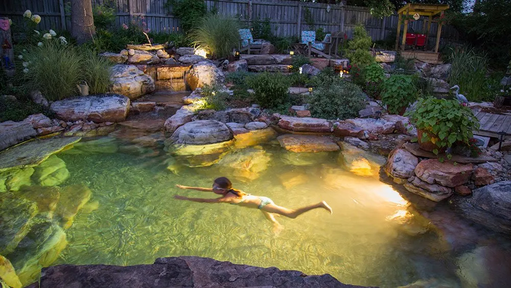 Young girl swimming in Natural Pond Pool with lighting for nighttime swimming