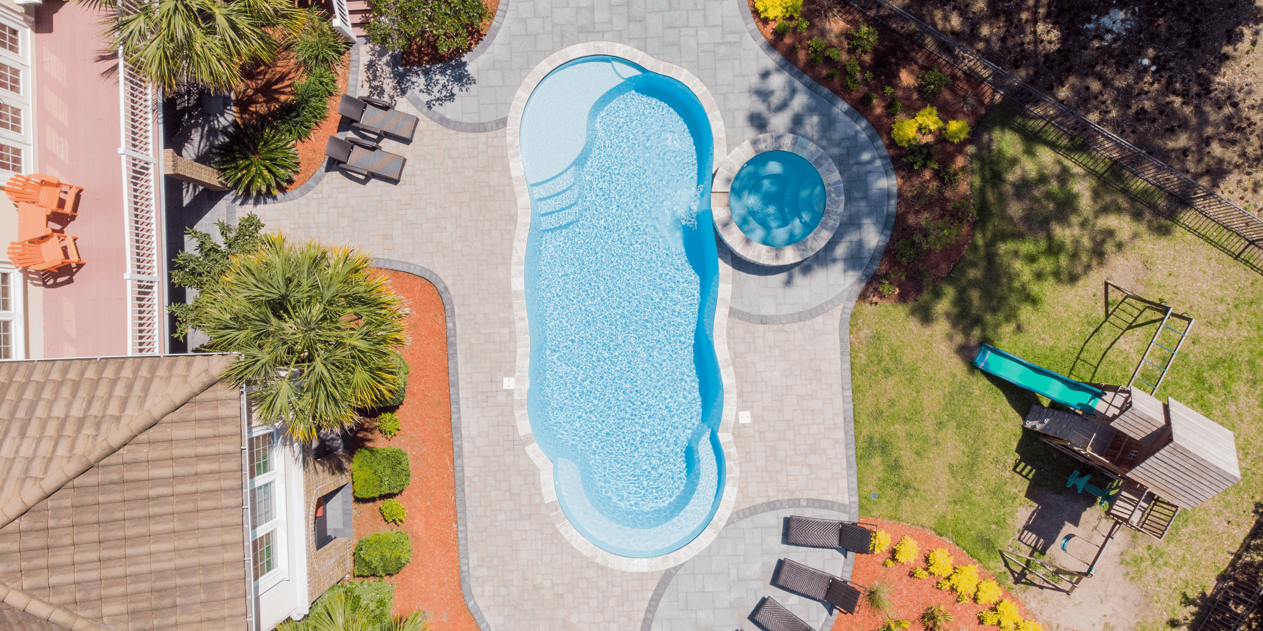 Complete pool project with River Pools C40 with spillway in Caribbean Sparkle with concrete paver patio and natural stone coping