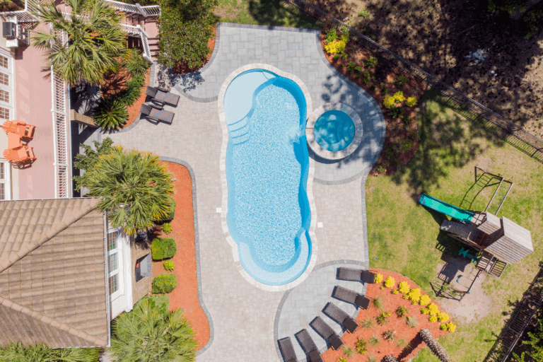 River Pools C40 Complete pool project with River Pools C40 with spillway in Caribbean Sparkle with concrete paver patio and natural stone coping