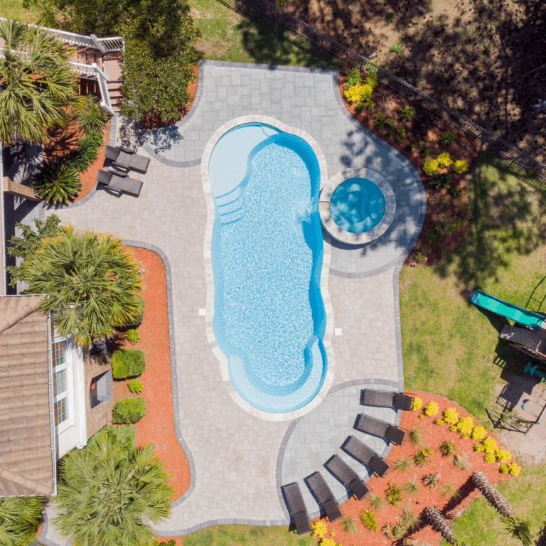 Complete pool project with River Pools C40 with spillway in Caribbean Sparkle with concrete paver patio and natural stone coping